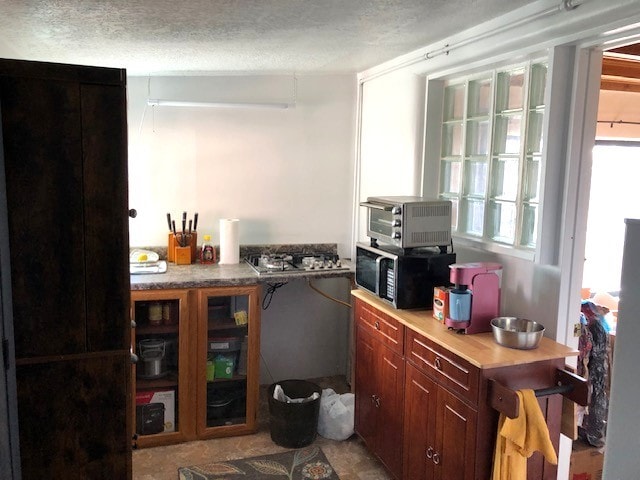 bar with a toaster, stainless steel gas cooktop, black microwave, and a textured ceiling