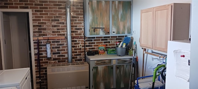 interior space featuring heating unit, brick wall, light countertops, and washing machine and clothes dryer