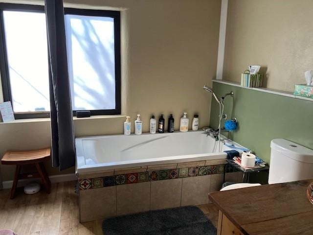 bathroom featuring toilet, a garden tub, and wood finished floors