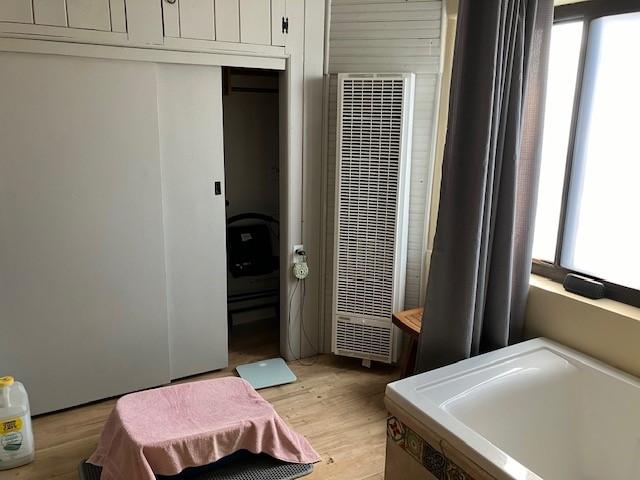 bedroom with light wood-type flooring, a closet, and a heating unit