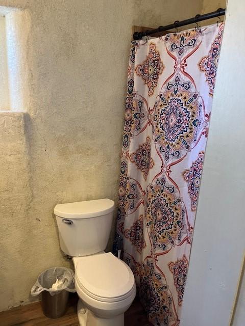 full bath with toilet, a shower with curtain, and wood finished floors