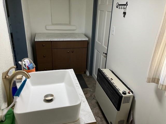 bathroom featuring heating unit and a sink