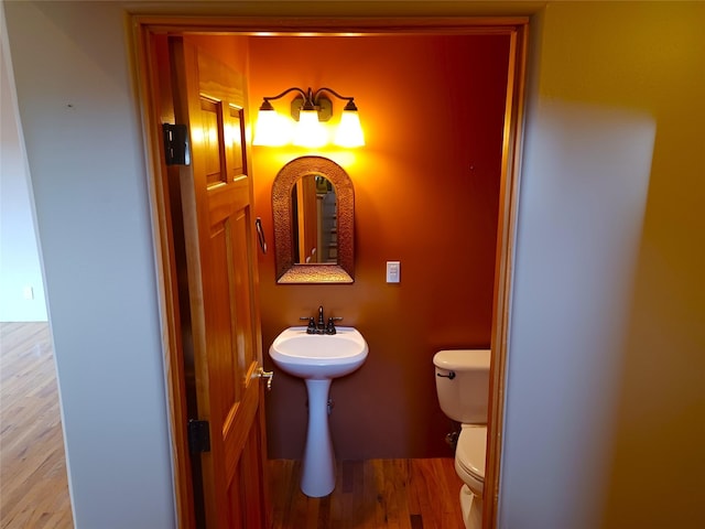 half bathroom with toilet and wood finished floors