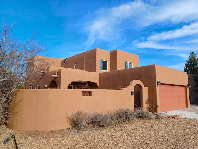 southwest-style home with a garage, driveway, a fenced front yard, and stucco siding