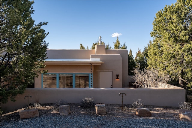 pueblo-style home featuring fence and stucco siding