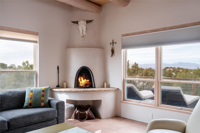 living room featuring a lit fireplace, a mountain view, and beamed ceiling