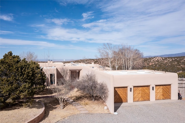 pueblo-style house featuring a garage and stucco siding