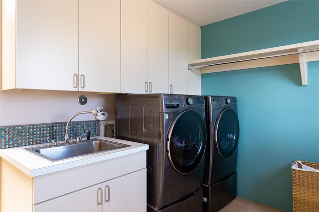 washroom with cabinet space, a sink, and washing machine and clothes dryer