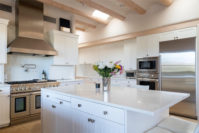 kitchen featuring tasteful backsplash, visible vents, a kitchen island, built in appliances, and wall chimney exhaust hood