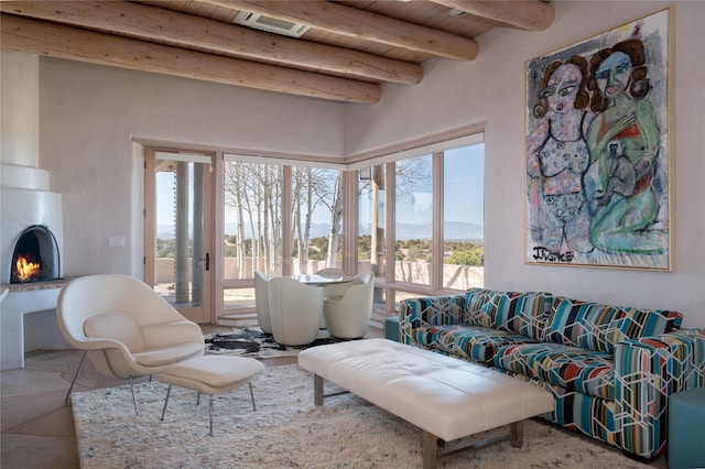 living room with wooden ceiling, a fireplace, beamed ceiling, and visible vents