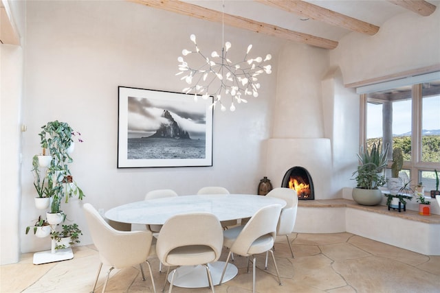 dining space with a fireplace, a chandelier, and beam ceiling