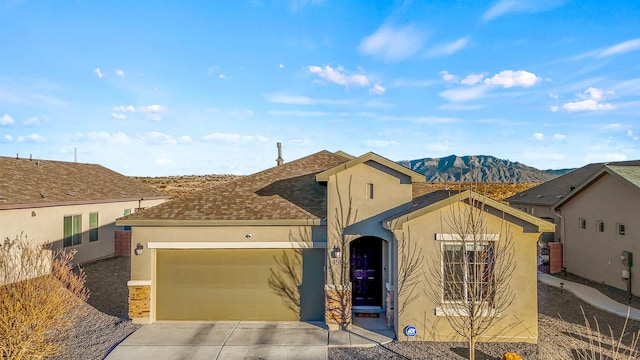 view of front of property featuring stucco siding, a mountain view, roof with shingles, concrete driveway, and an attached garage