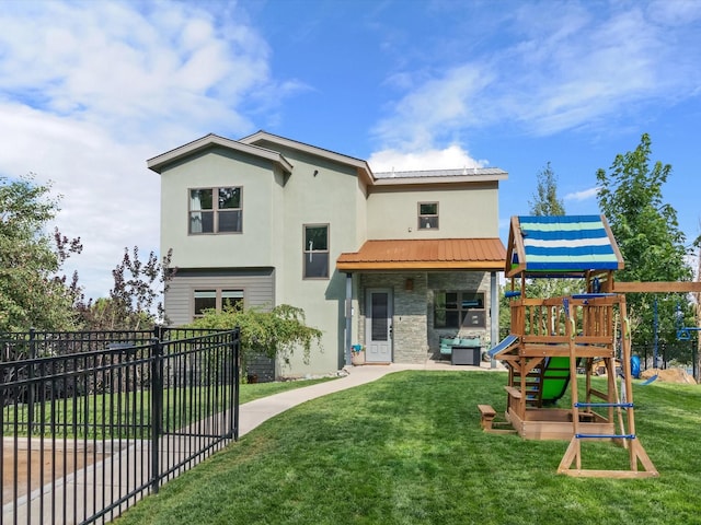 exterior space with a playground, stucco siding, a lawn, metal roof, and fence