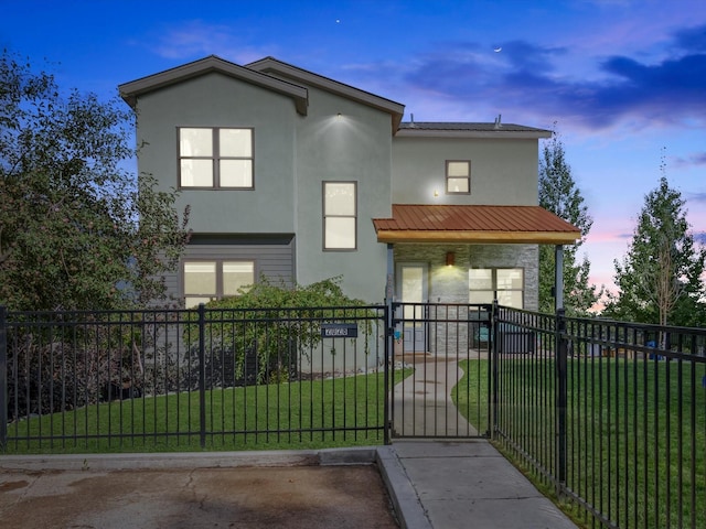 view of front of property with metal roof, a fenced front yard, a gate, stucco siding, and a front lawn