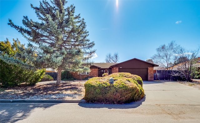 ranch-style house with a garage, concrete driveway, brick siding, and fence