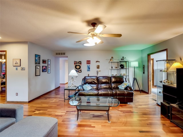 living area with light wood-type flooring, visible vents, ceiling fan, and baseboards