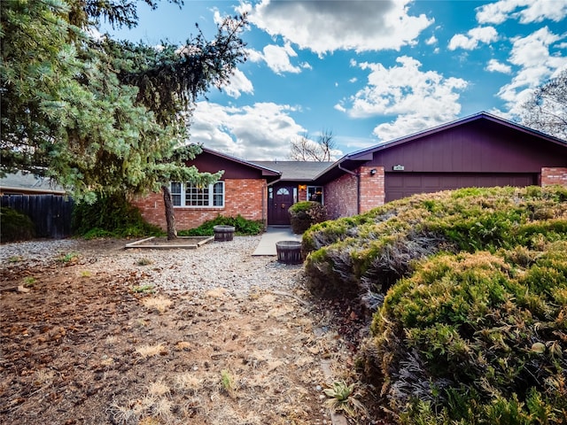 ranch-style house with an attached garage, fence, and brick siding