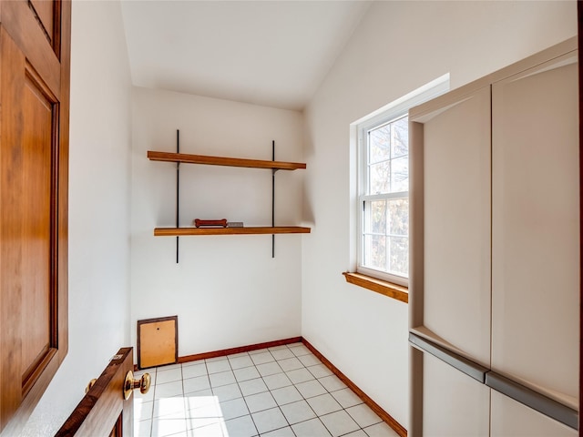 unfurnished room featuring lofted ceiling, baseboards, and light tile patterned floors