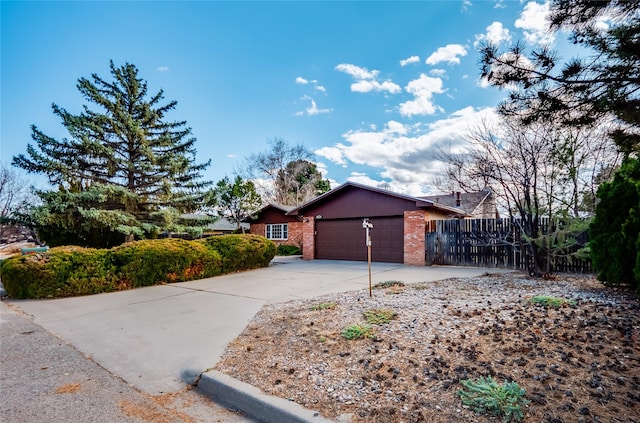 view of front of home featuring an attached garage, fence, concrete driveway, and brick siding