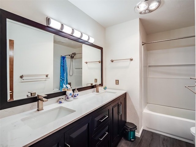 bathroom featuring double vanity, shower / bathtub combination with curtain, a sink, and wood finished floors