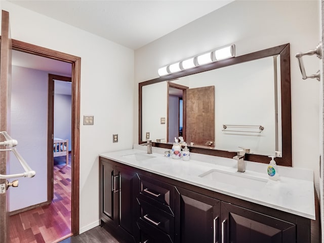 full bathroom with double vanity, wood finished floors, a sink, and baseboards