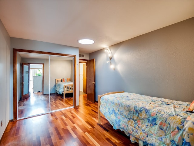 bedroom featuring a closet, visible vents, and wood finished floors