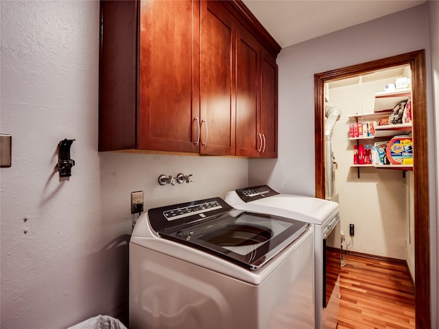 laundry room featuring light wood-style flooring, washer and clothes dryer, and cabinet space