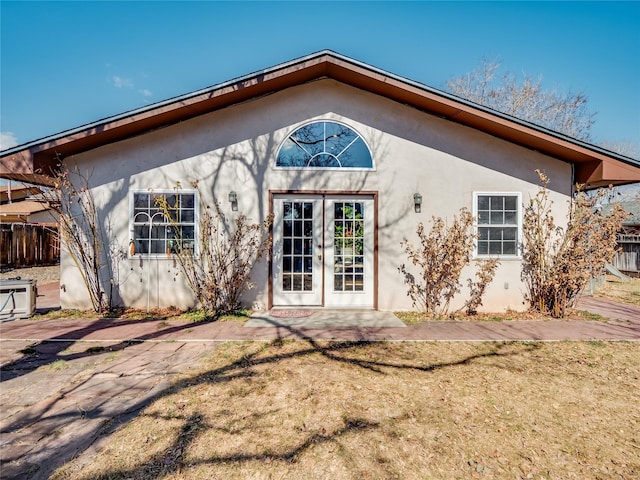 exterior space with a yard, french doors, fence, and stucco siding