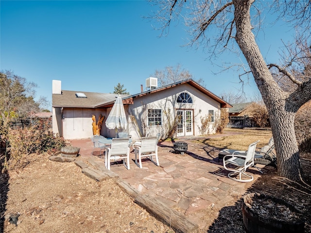 rear view of house with central AC unit, french doors, a chimney, and a patio area