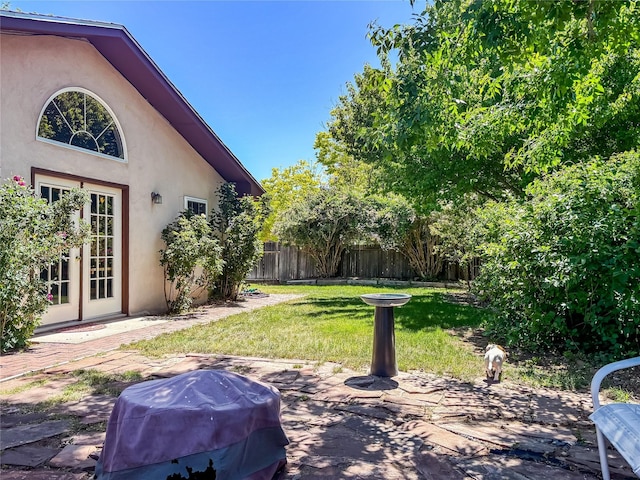 view of yard with fence, a patio, and french doors