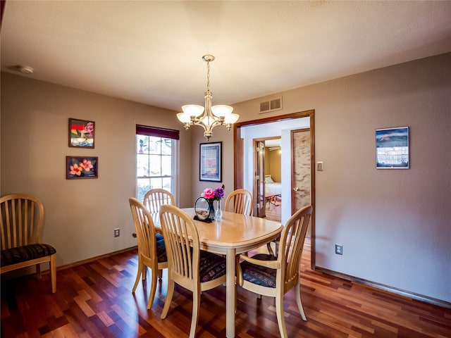 dining space with baseboards, visible vents, a chandelier, and wood finished floors