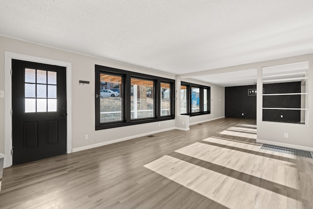 foyer featuring a textured ceiling, wood finished floors, visible vents, and baseboards