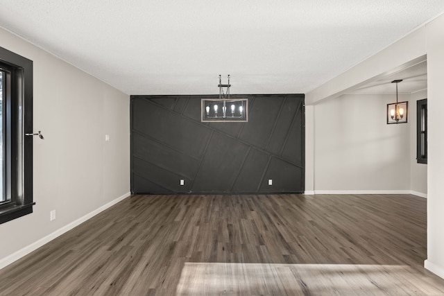 below grade area featuring an inviting chandelier, baseboards, and wood finished floors