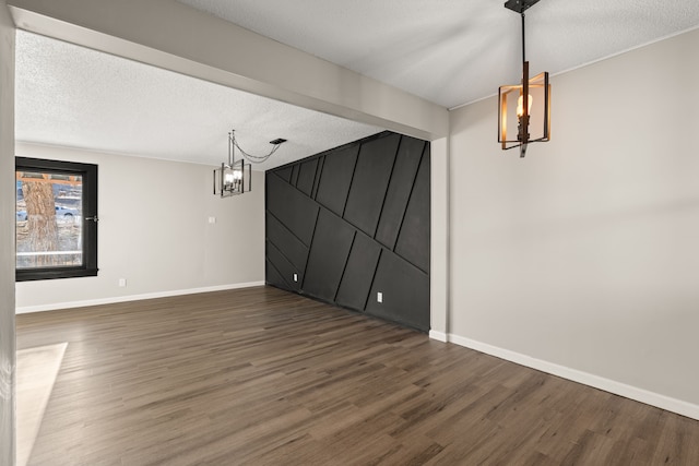 unfurnished dining area featuring a notable chandelier, a textured ceiling, and wood finished floors