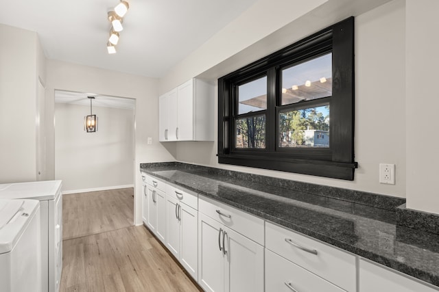 kitchen featuring white cabinets, independent washer and dryer, light wood finished floors, and dark stone countertops