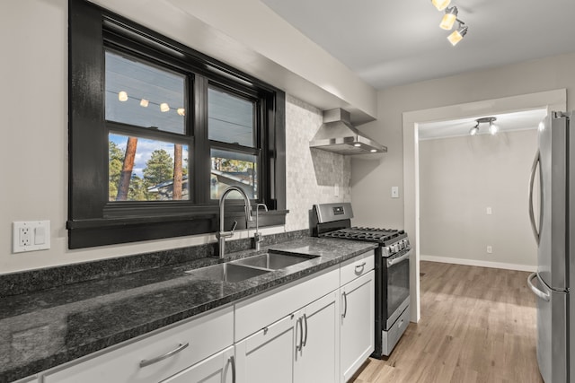 kitchen with a sink, white cabinetry, appliances with stainless steel finishes, light wood-type flooring, and wall chimney exhaust hood