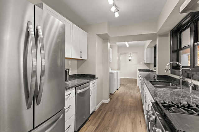 kitchen with washing machine and clothes dryer, light wood-style flooring, appliances with stainless steel finishes, white cabinets, and a sink