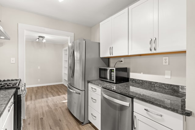 kitchen featuring baseboards, white cabinets, appliances with stainless steel finishes, dark stone countertops, and light wood-type flooring