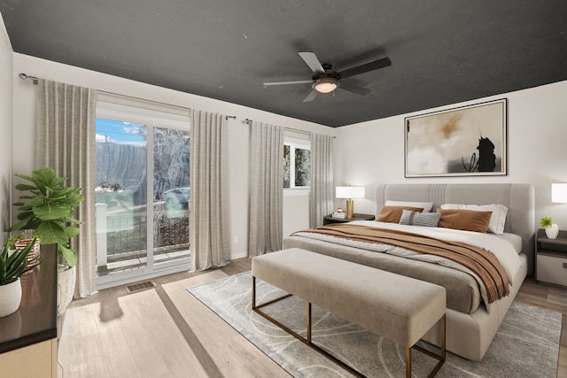 bedroom featuring access to exterior, a ceiling fan, visible vents, and wood finished floors