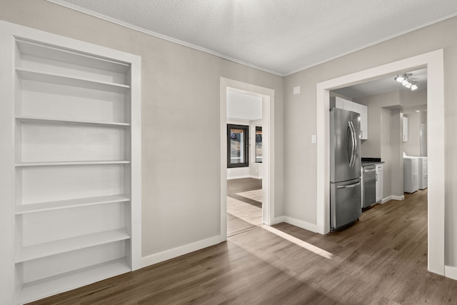 interior space with washer / dryer, built in features, baseboards, dark wood-style flooring, and a textured ceiling