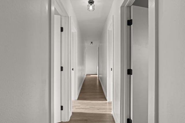 hall with baseboards and wood finished floors