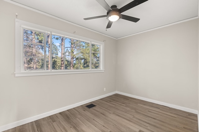 unfurnished room with baseboards, visible vents, a ceiling fan, ornamental molding, and wood finished floors