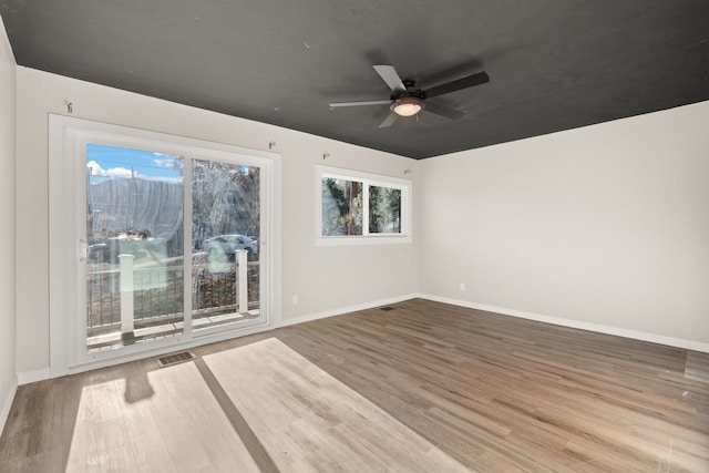 empty room with visible vents, ceiling fan, baseboards, and wood finished floors