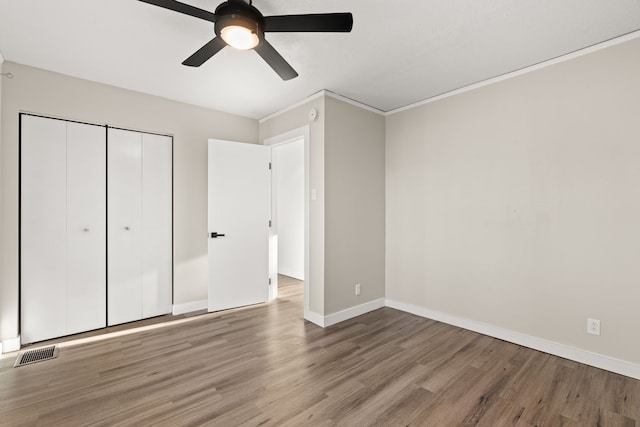 unfurnished bedroom featuring baseboards, a closet, visible vents, and wood finished floors