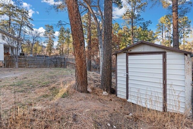 view of yard featuring an outbuilding, a shed, a detached garage, and fence