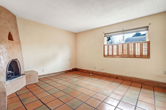 unfurnished living room featuring a textured ceiling, a fireplace, light tile patterned flooring, and baseboards