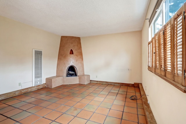 unfurnished living room with a large fireplace, visible vents, baseboards, tile patterned flooring, and a textured ceiling