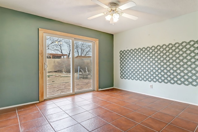 spare room with dark tile patterned floors, a ceiling fan, and baseboards