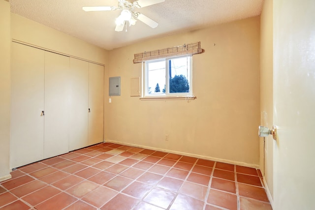 unfurnished bedroom featuring a closet, a ceiling fan, light tile patterned flooring, a textured ceiling, and electric panel