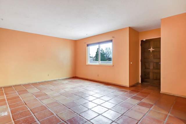 empty room with light tile patterned floors and baseboards